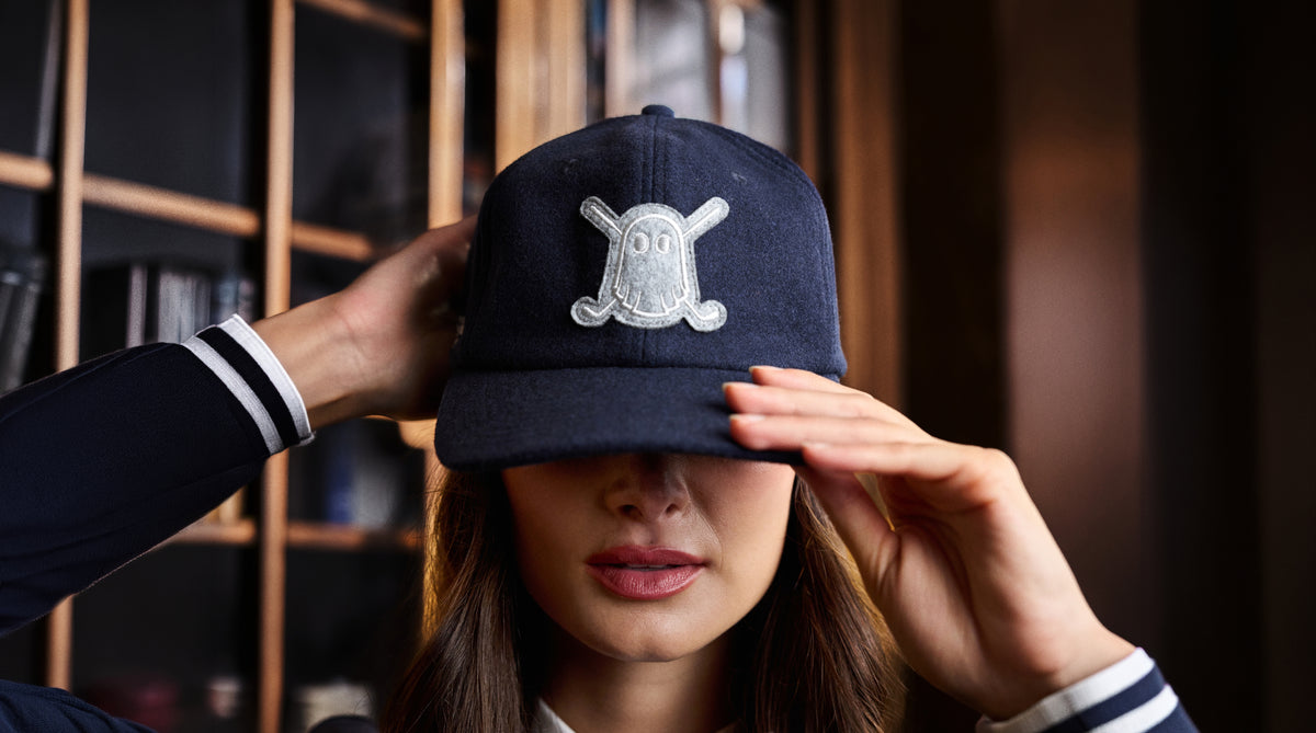 Lifestyle image of a female model adjusting her hat, showcasing an embroidered Ghost Golf Icon logo patch on the front.