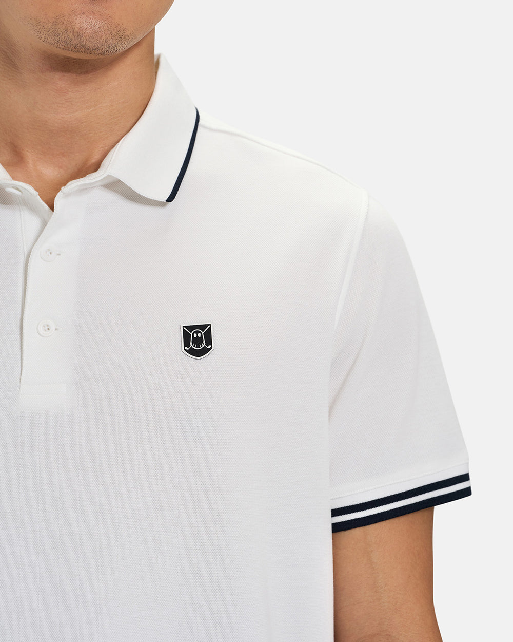 Front Closeup View of White Spectator Tipped Collar Polo on Asian Male Model with Ghost Icon Crest #color_white
